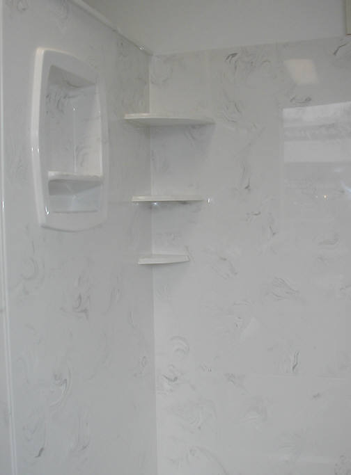 Light gray and white cultured marble shower with recessed storage and corner shelves